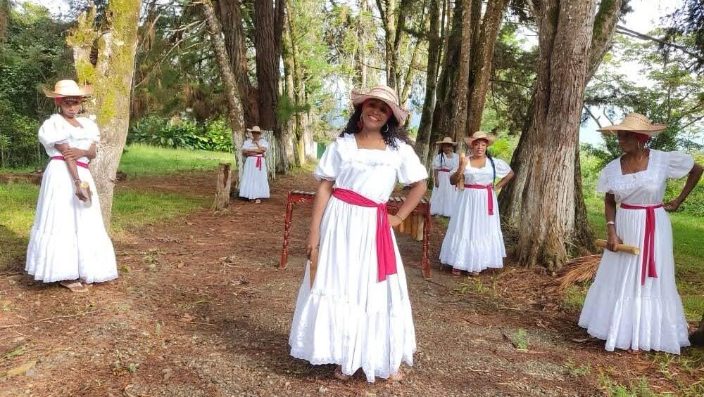 Cantaoras de Sonidos Profundos con traje tradicional blanco, entre los árboles